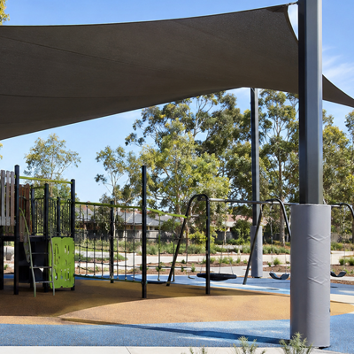 Protective post pads fitted around shade sail posts in a playground
